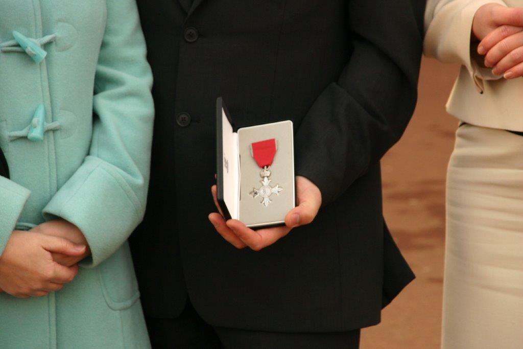 Man holding up an MBE medal