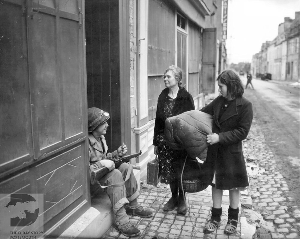 A US soldier talks to two French women, in the town of Ste. Mere Eglise